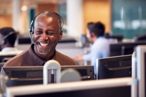 mature businessman wearing telephone headset talking to caller in customer services department